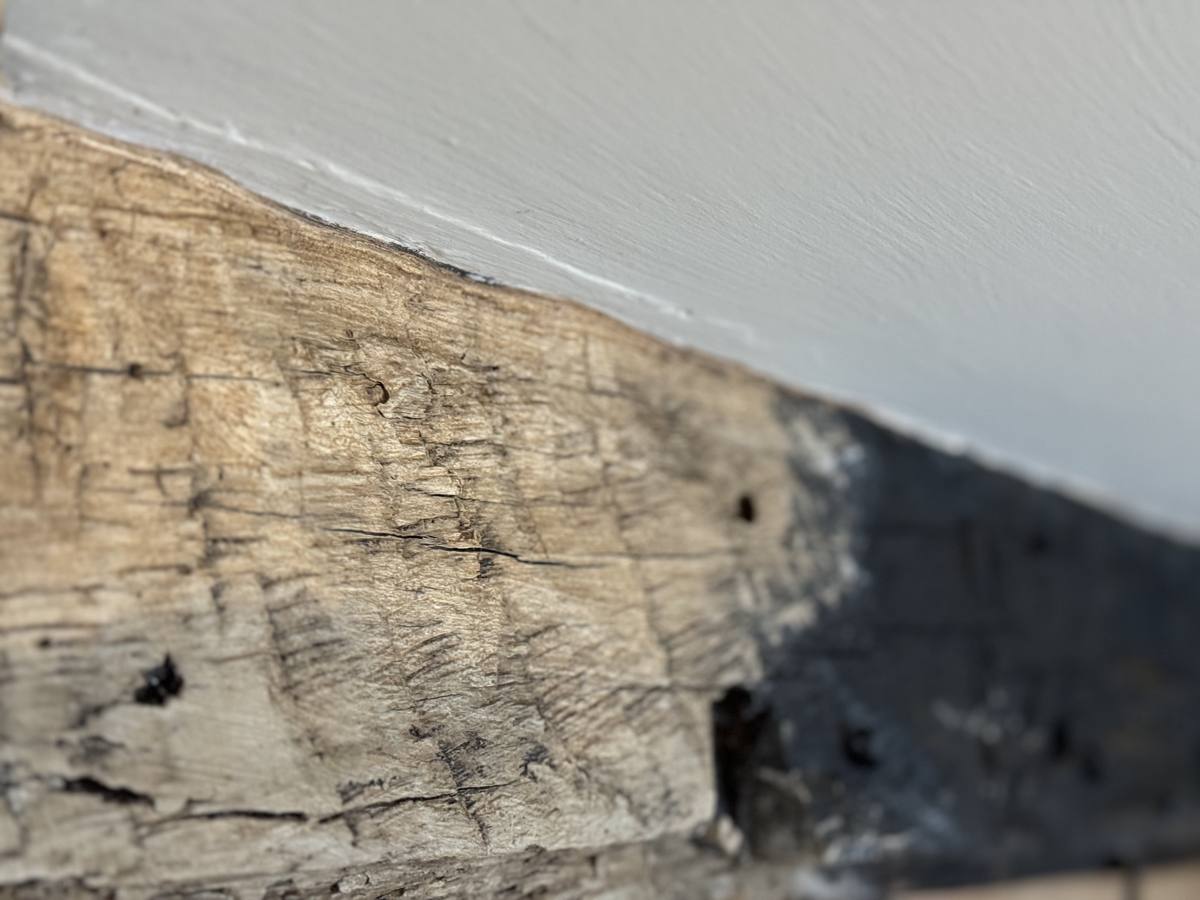 Oak beam part-way through restoration, the cleaned timber meeting the original blackened surface