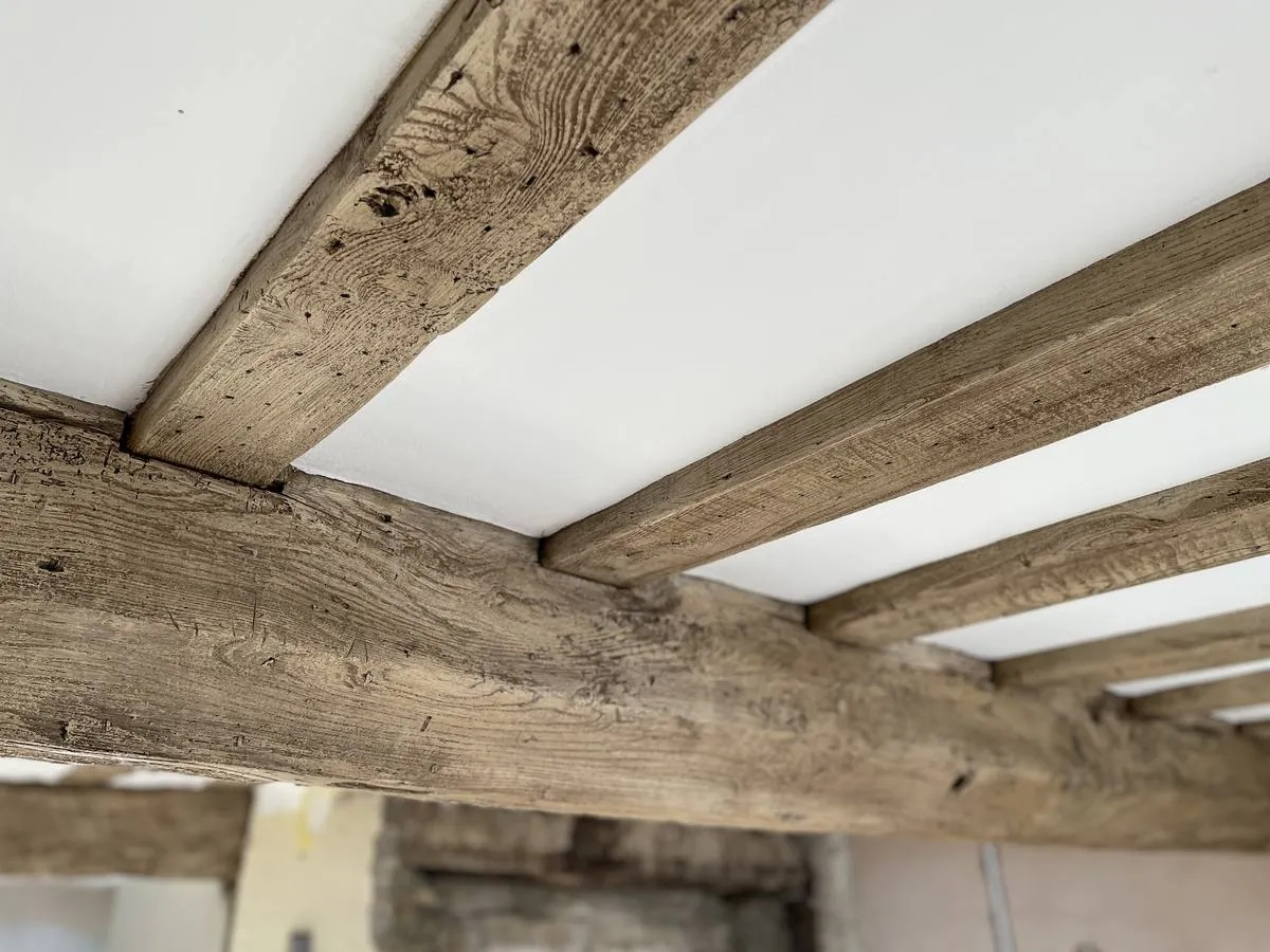 Close detail of restored ceiling beams showing natural grain and tool marks