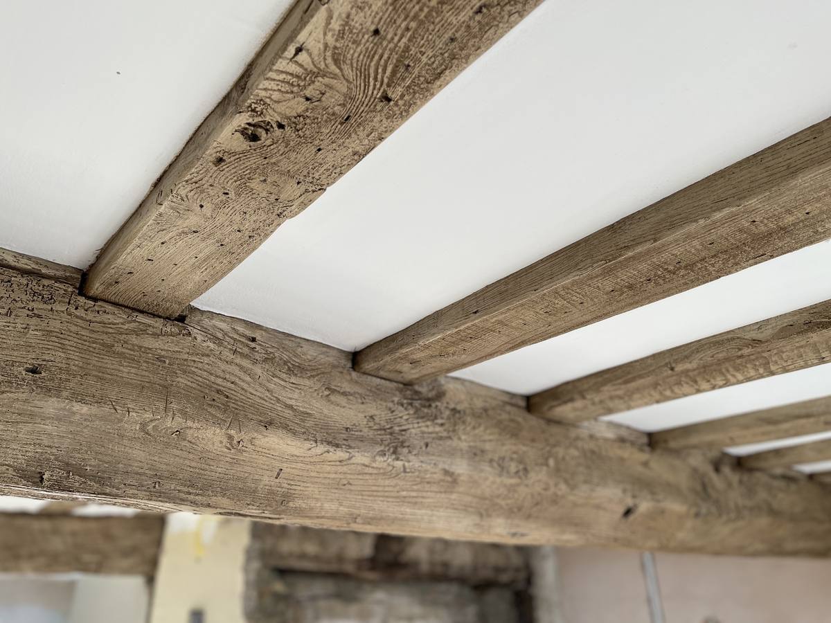 Close detail of restored ceiling beams showing natural grain and tool marks